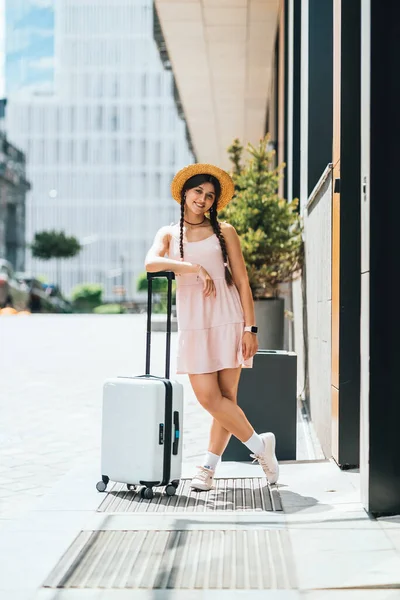 Young beautiful woman with a suitcase on the background of a modern city