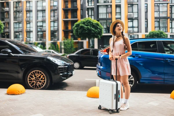 Young beautiful woman with a suitcase on the background of a modern city