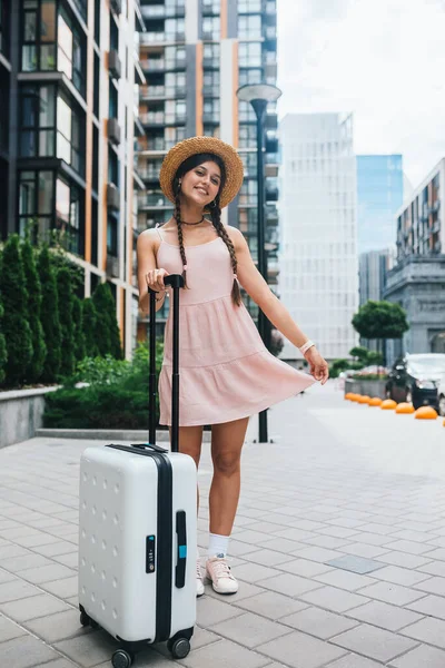 Young beautiful woman with a suitcase on the background of a modern city