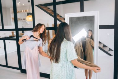 Image of pretty females trying on dress at home