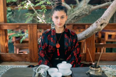 önünde çay seti ve aroma sopa, meditasyon poz oturan genç bir bayan. gevşeme kavramı