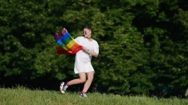 Young woman with lgbt pride flag walking in the park.