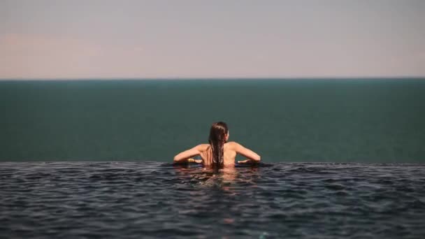 Счастливая Женщина Купальнике Плавает Бесконечном Бассейне Роскошном Отеле Фоне Моря — стоковое видео