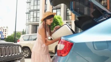 Woman takes out a suitcase from the trunk of a car. Holidays concept.