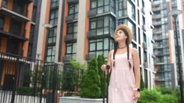 Genç ve güzel bir kadın bir bavulla yürüyor.