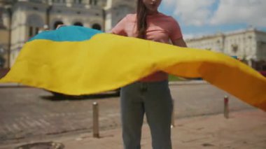 Ukrayna bayrağı taşıyan genç bir kadın şehirde yürüyor.