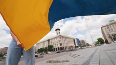 Ukrayna bayrağı taşıyan genç bir kadın şehirde yürüyor.