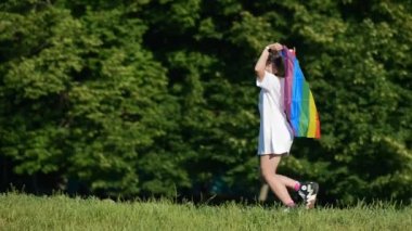 Young woman with lgbt pride flag walking in the park.