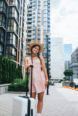 Young beautiful woman with a suitcase on the background of a modern city