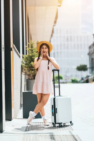 Young beautiful woman with a suitcase on the background of a modern city