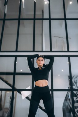 Spor takım elbiseli, evde gülümseyen aerobik antrenmanı yapan sevimli genç bir kızın fotoğrafı.