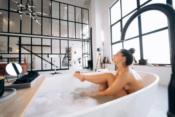 Donna Strofinando Gamba Con Spugna Mentre Bagno — Foto Stock