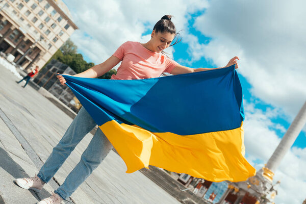 Young woman holding national flag of Ukraine in the city