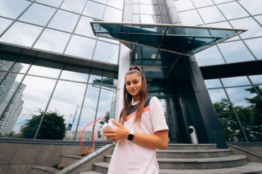 Sporcu kadın, modern binanın arka planında poz veriyor. Şehir içinde yürüyor.