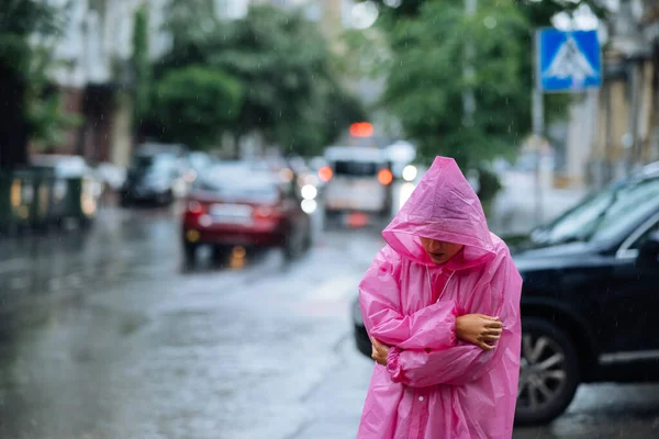 Sad woman in a raincoat on the street on a rainy day.