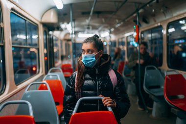 Otobüsle seyahat eden maskeli genç bir kadın. Coronavirus solunum yolunun eşsiz koruyucu maskesi..