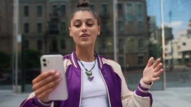 Close-up of a smiling brunette girl who communicates by video call on the background of street