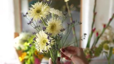 Çiçekçi kadın taze kır çiçeklerinden bir buket yapar. Yakın görünüm