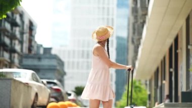 A young beautiful woman walks with a white suitcase