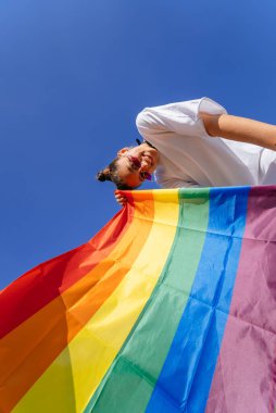 Genç bir kadın, LGBT toplumunu desteklemek için gökyüzüne gökkuşağı bayrağı dikiyor.