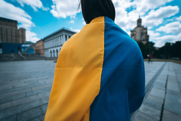 Young woman with national flag of Ukraine walking in the city