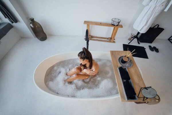 Pretty young woman taking bath at home