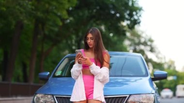 Woman using smartphone near car on road