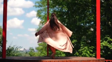 Kadın mankenlik yapıyor, terasta dans ediyor, bornoz giyiyor ve gülümsüyor.