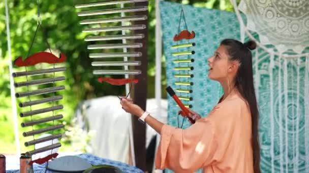 一位年轻漂亮的妇女在花园里弹奏乐器 管状铃铛 — 图库视频影像