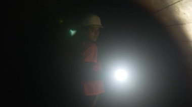 Elinde fener olan genç bir kadın kazıcı tüneli keşfediyor.