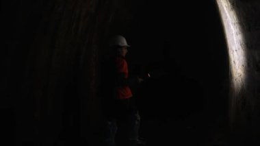 Elinde fener olan genç bir kadın kazıcı tüneli keşfediyor.