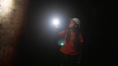 Elinde fener olan genç bir kadın kazıcı tüneli keşfediyor.