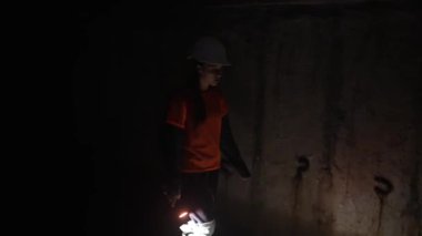 Elinde fener olan genç bir kadın kazıcı tüneli keşfediyor.