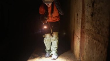 Elinde fener olan genç bir kadın kazıcı tüneli keşfediyor.