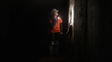 Elinde fener olan genç bir kadın kazıcı tüneli keşfediyor.