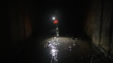 Elinde fener olan genç bir kadın kazıcı tüneli keşfediyor.