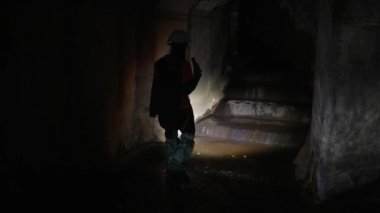 Elinde fener olan genç bir kadın kazıcı tüneli keşfediyor.