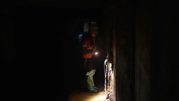 一个拿着手电筒的年轻女挖掘机探索隧道 — 图库视频影像