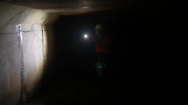 Elinde fener olan genç bir kadın kazıcı tüneli keşfediyor.