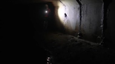 Elinde fener olan genç bir kadın kazıcı tüneli keşfediyor.