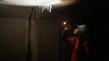 Elinde fener olan genç bir kadın kazıcı tüneli keşfediyor.