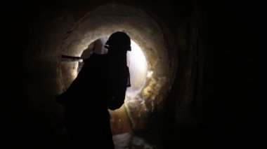 Elinde fener olan genç bir kadın kazıcı tüneli keşfediyor.