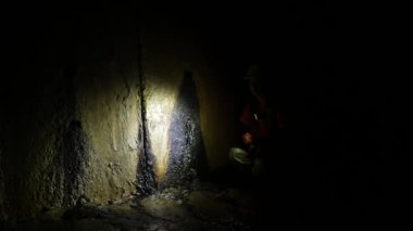 Elinde fener olan genç bir kadın kazıcı tüneli keşfediyor.