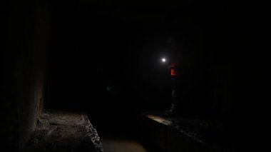 Elinde fener olan genç bir kadın kazıcı tüneli keşfediyor.