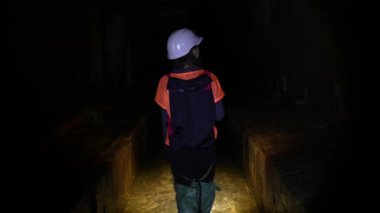 Elinde fener olan genç bir kadın kazıcı tüneli keşfediyor.