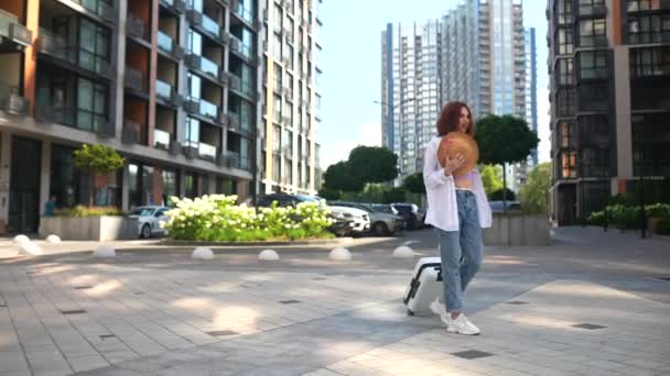 Uma Mulher Ruiva Com Uma Mala Caminha Pela Cidade Moderna — Vídeo de Stock