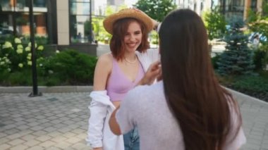 Dostça bir konuşma. Konuşan ve dışarıda duran iki güzel genç kadının yan görüntüsü.