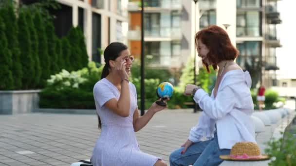 2人の若い女性が手に地球と街の通りにいる 旅行のコンセプト — ストック動画