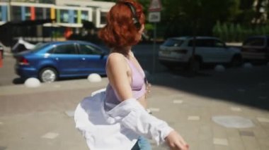 Neşeli stil sahibi, sıradan bir öğrenci kadın şehirde dolaşırken siyah kablosuz kulaklıklar kullanarak müzik dinlemekten hoşlanıyor..