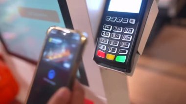 Akıllı adamların akıllı telefonlarını tuttukları ve kredi kartı okuyucularında NFC teknolojisi kullanarak ödeme yaptıkları görüntüler.